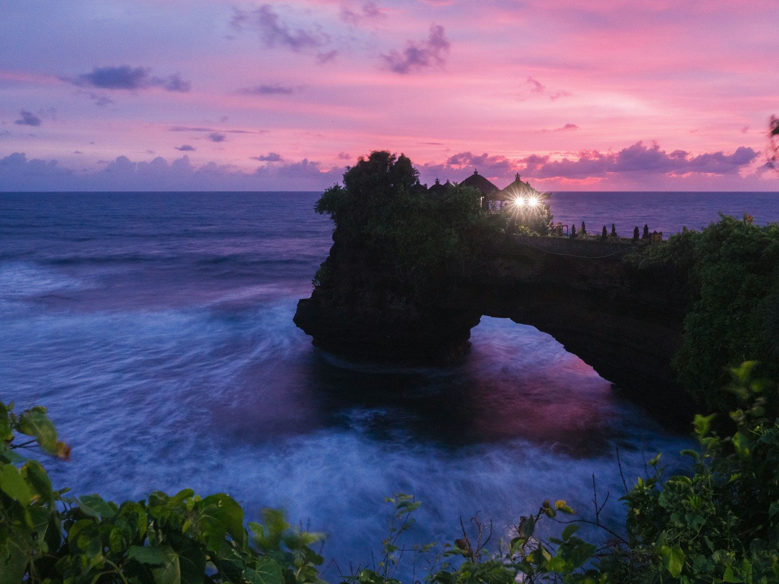Temple on a rock arch over the ocean at sunset